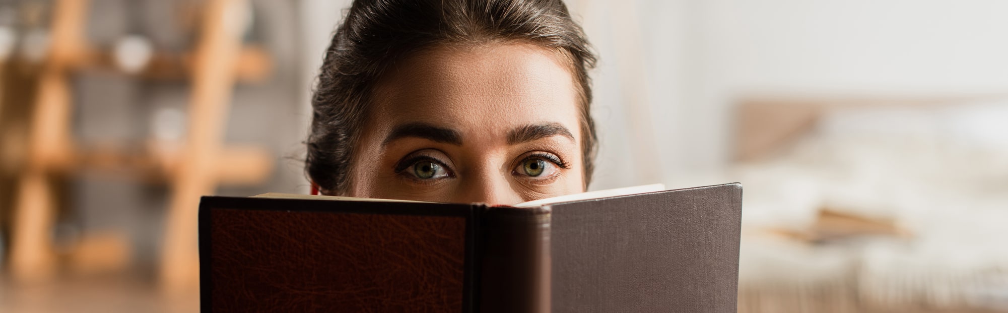Foto stock - donna che nasconde il viso tenendo il libro e guardando la fotocamera
